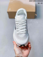 Top view of the white lace-up sneaker showing the mesh-like forefoot, tongue branding, and gray details.