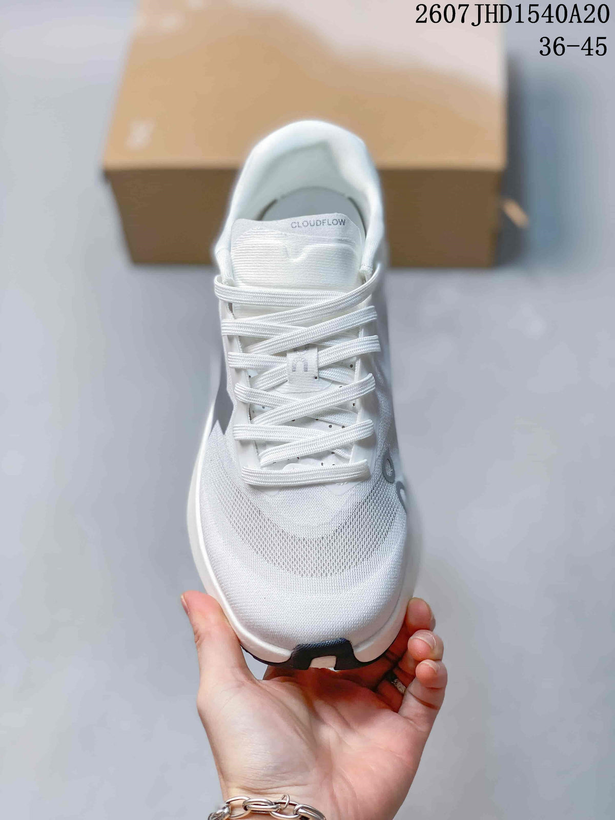 Top view of the white lace-up sneaker showing the mesh-like forefoot, tongue branding, and gray details.