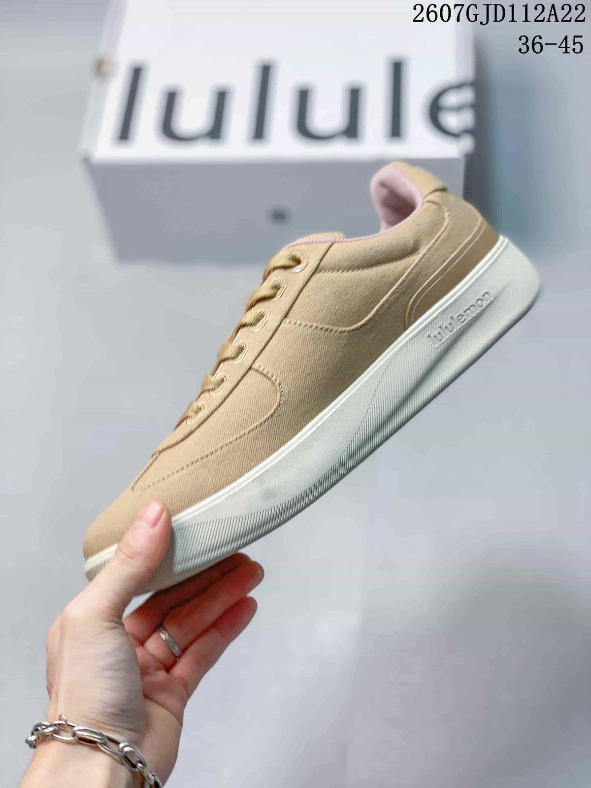 Side view of the tan low-top sneaker showing tonal panels, laces and a light-colored sole.