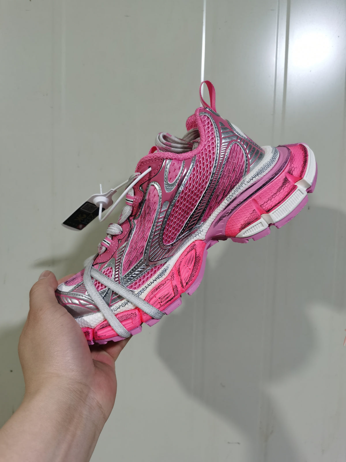 Side view of the pink and silver Nike sneaker showing layered overlays, mesh construction, and textured outsole sections.