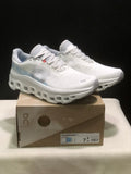 Pair of ivory and glacier On Cloudmonster 1 running shoes displayed on a branded shoe box; the box label shows EU 38 for the photographed sample.