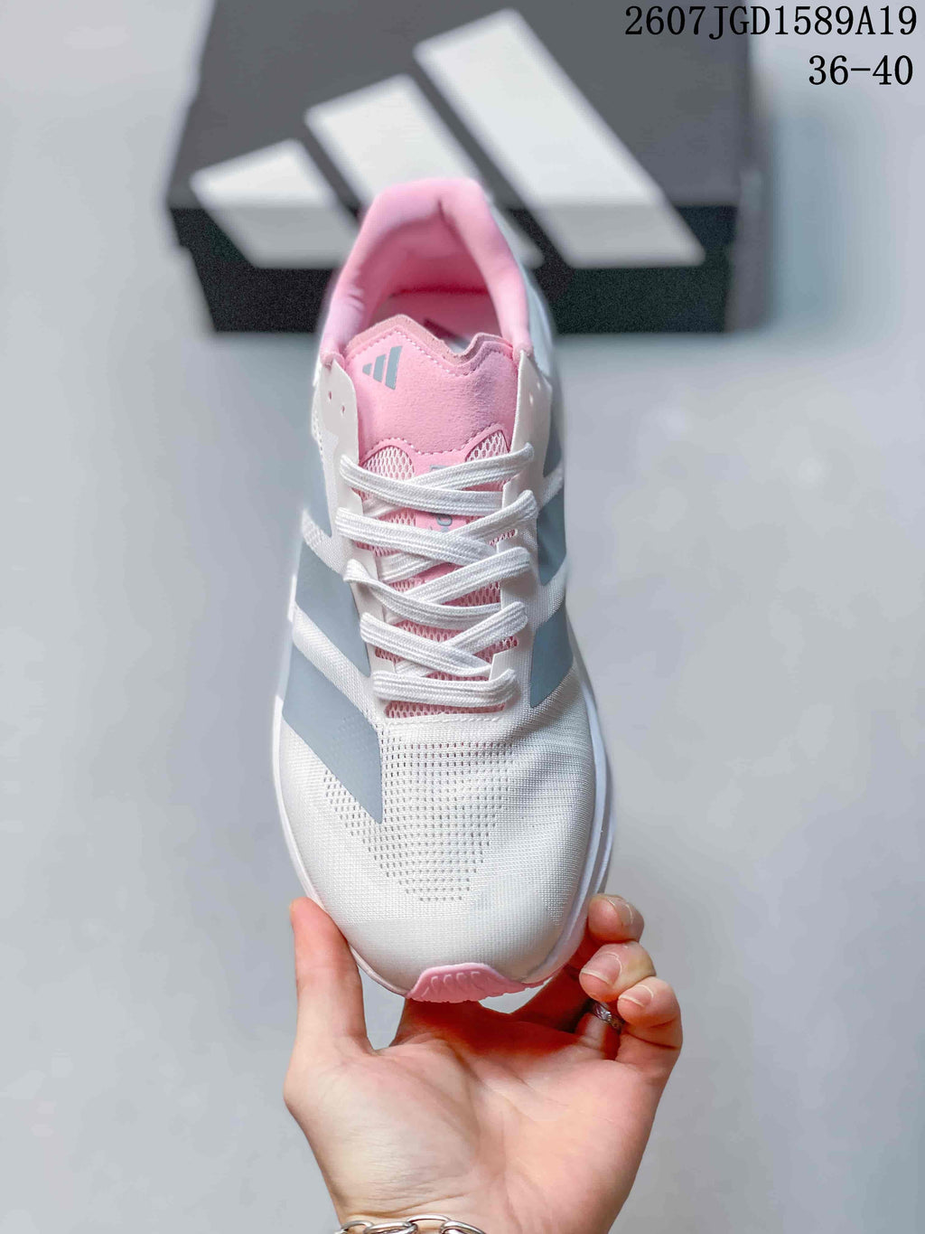 Top view of the sneaker showing white laces, a pink tongue, gray branding and a perforated-looking toe area.
