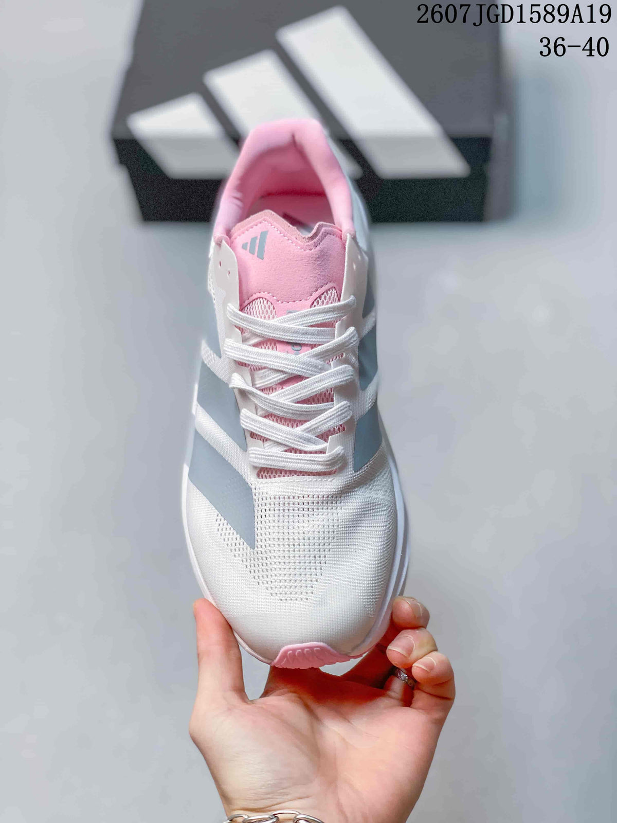 Top view of the sneaker showing white laces, a pink tongue, gray branding and a perforated-looking toe area.