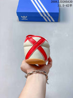 Rear view showing the heel stitching and gum-colored sole of the cream and red sneaker.