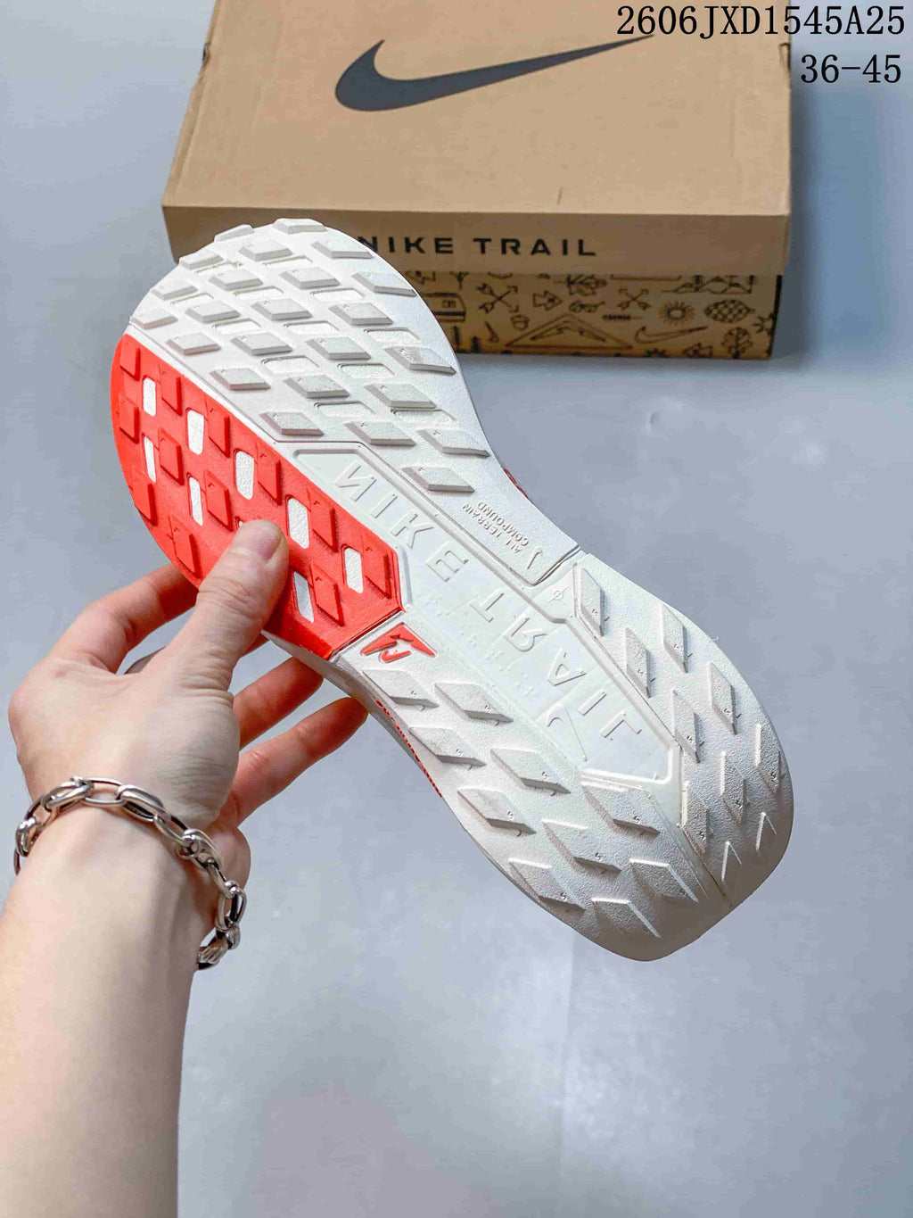 Close-up of the trail-style outsole with white and red tread