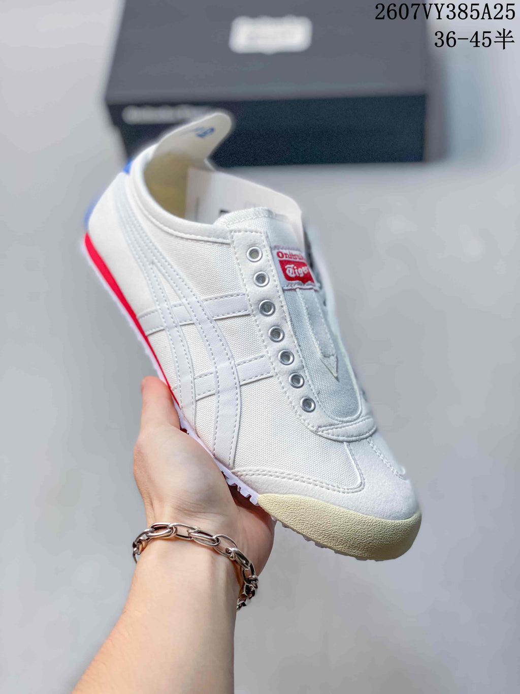 White Onitsuka Tiger slip-on sneaker with white side stripes, red accents and a cream-colored outsole.
