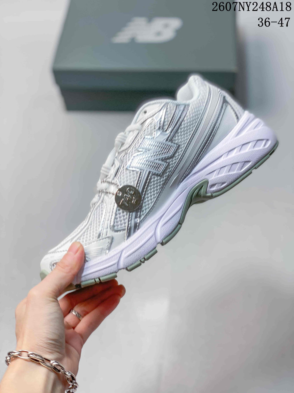 Side profile of the white and silver New Balance sneaker showing the layered upper and chunky sole.