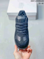 Front view of the black sneaker showing the rounded toe, tonal laces, stitched vamp panels, and numbered tongue detail.