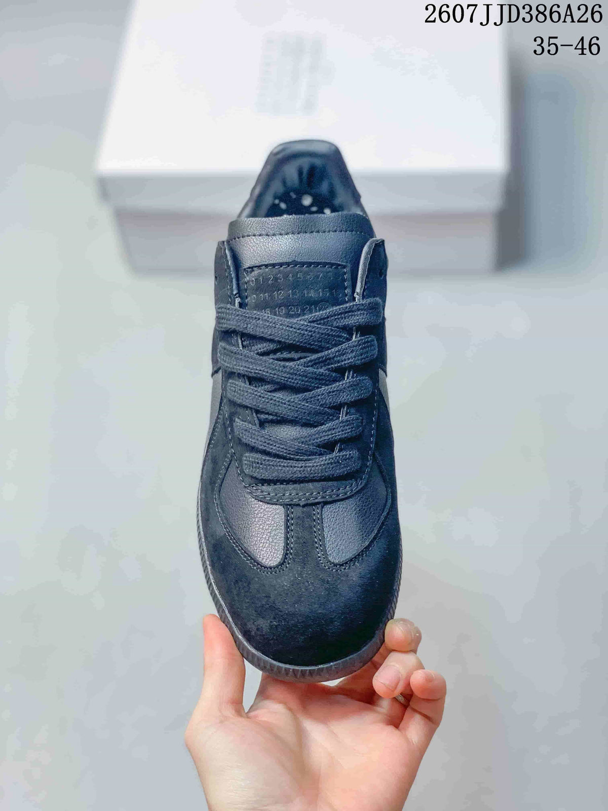 Front view of the black sneaker showing the rounded toe, tonal laces, stitched vamp panels, and numbered tongue detail.