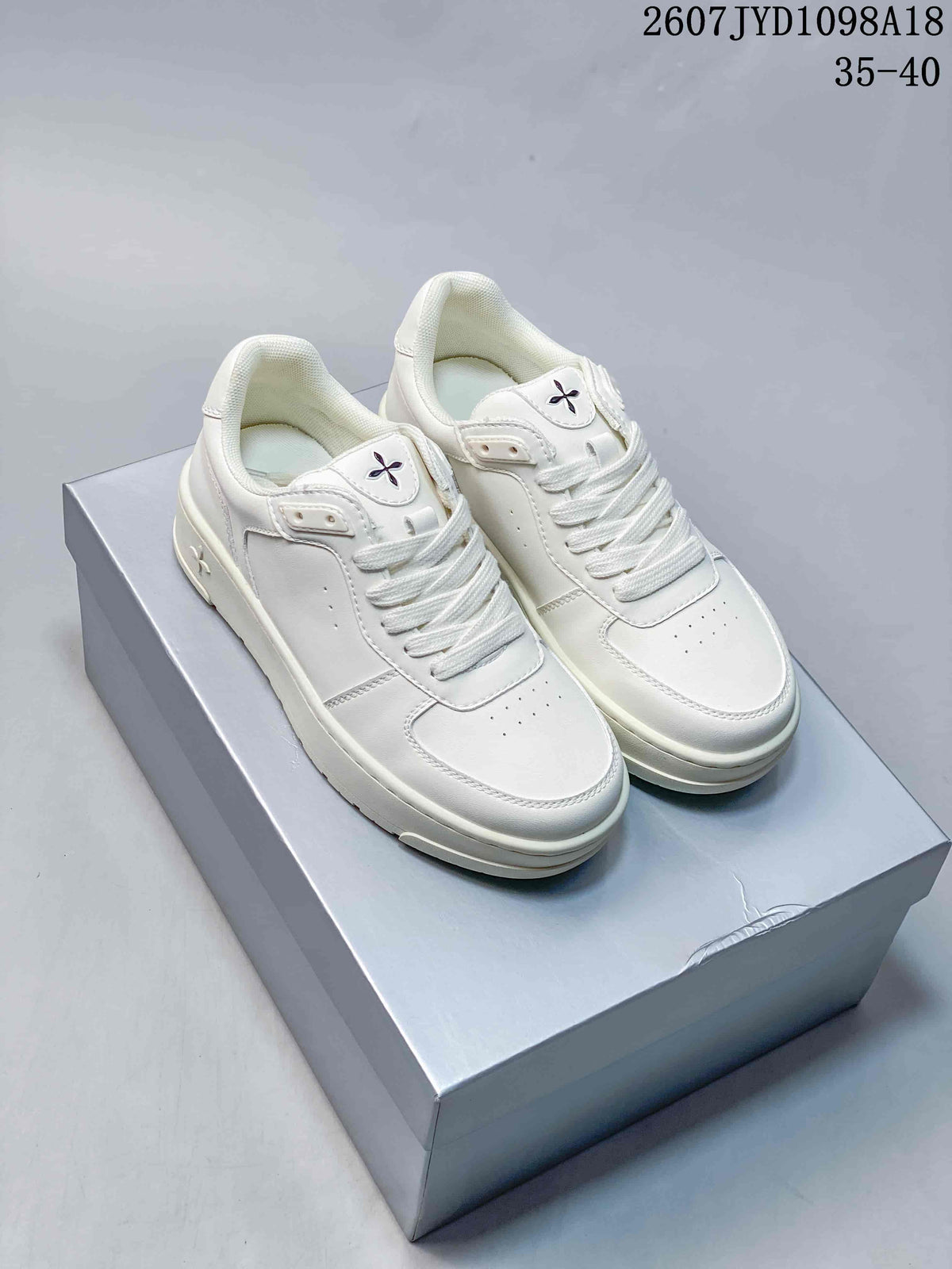 Pair of all-white SMFK low-top sneakers displayed on a shoebox, featuring white laces and a layered sole.