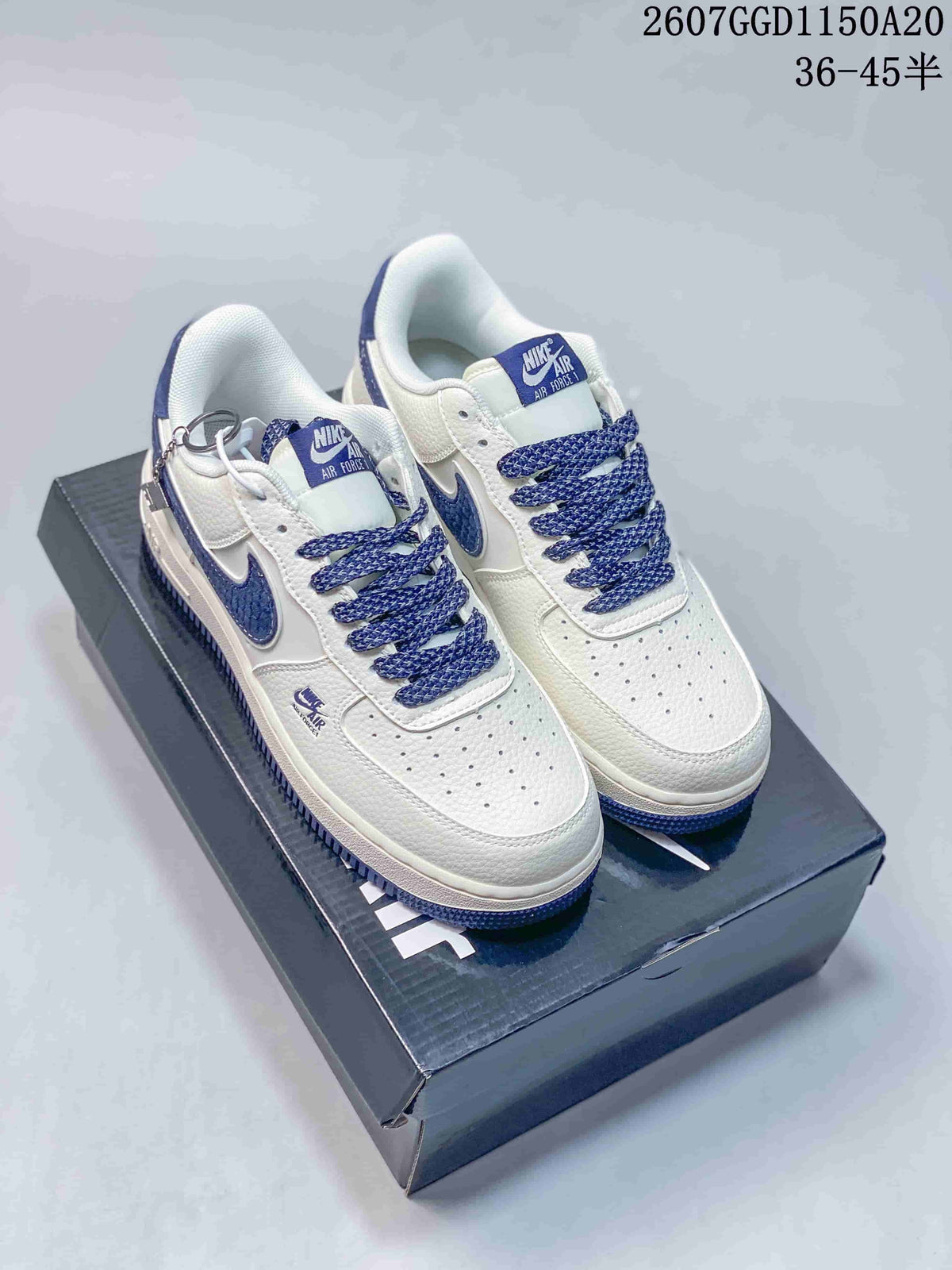 Pair of white Nike Air Force 1 '07 Low sneakers with blue Swoosh branding and blue laces displayed on a shoebox.