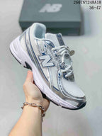 White and silver New Balance 740 sneaker with blue detailing.