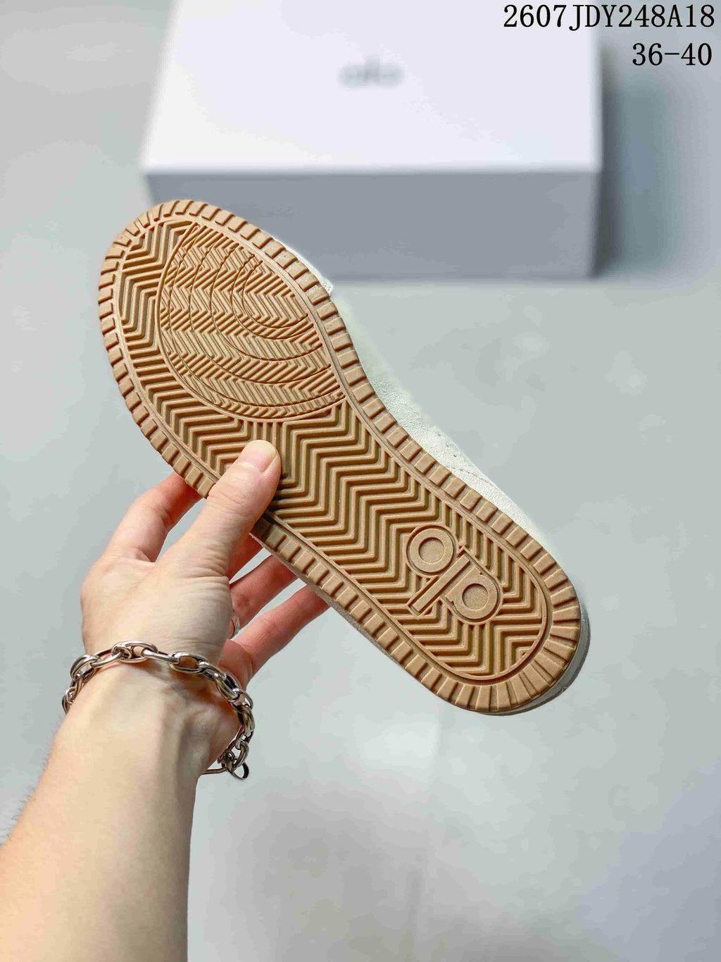 Underside view of a cream sneaker showing the patterned gum-colored outsole and tread.