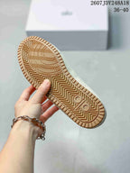 Underside view of a cream sneaker showing the patterned gum-colored outsole and tread.
