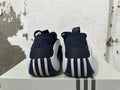 Rear view of navy and white Adidas basketball shoes showing ribbed heel details.