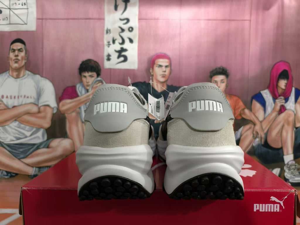Rear view of white and gray PUMA sneakers with black outsoles