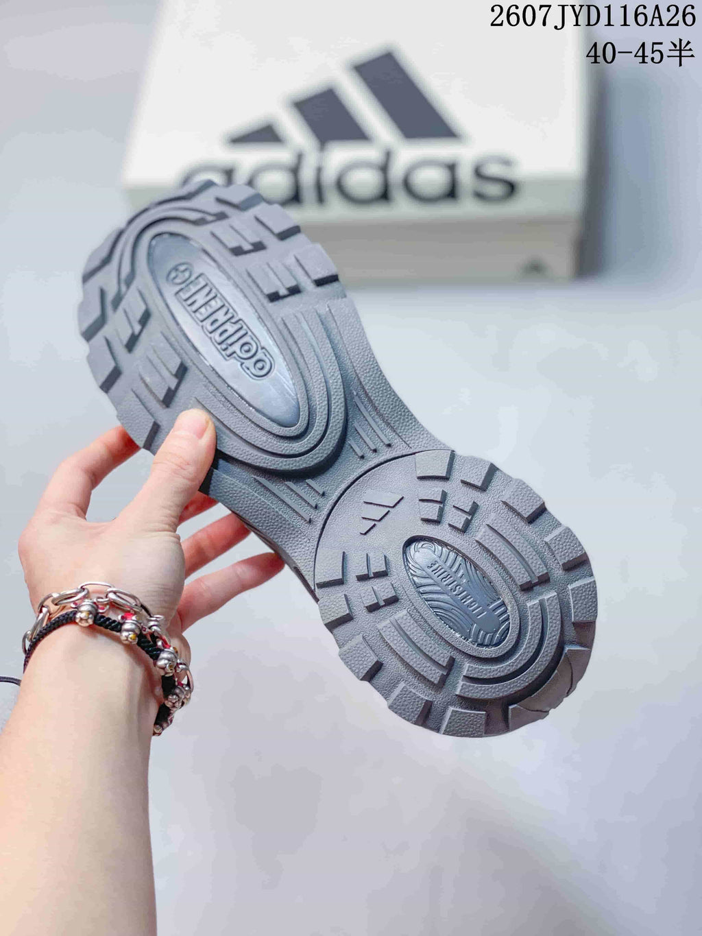 Close view of the gray sneaker outsole showing its deep, segmented tread pattern and molded sole details.