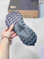 Close view of the dark gray sneaker outsole showing raised trail-style tread blocks and a textured midfoot area.