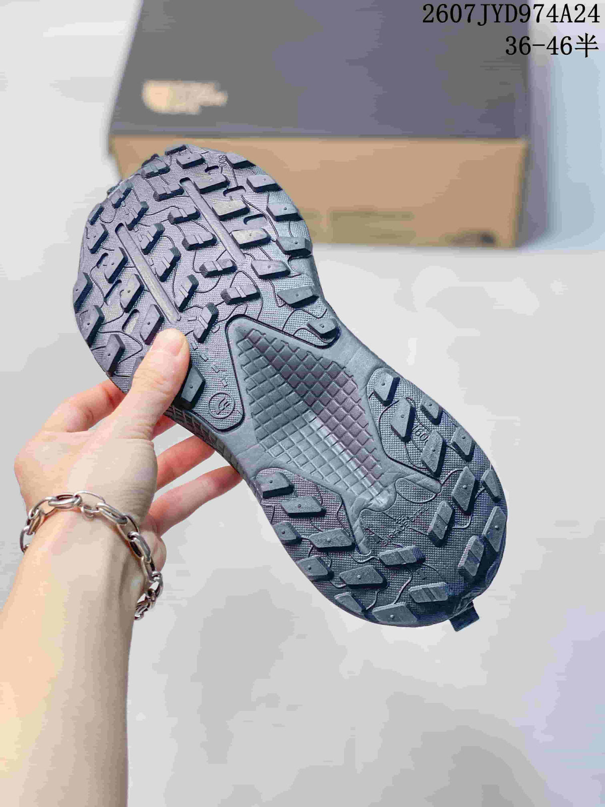Close view of the dark gray sneaker outsole showing raised trail-style tread blocks and a textured midfoot area.