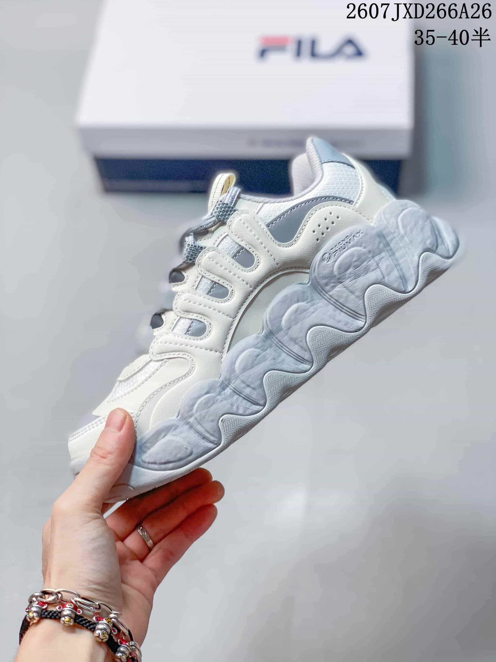 Side profile of the white and gray FILA sneaker showing layered panels and a chunky sculpted outsole.