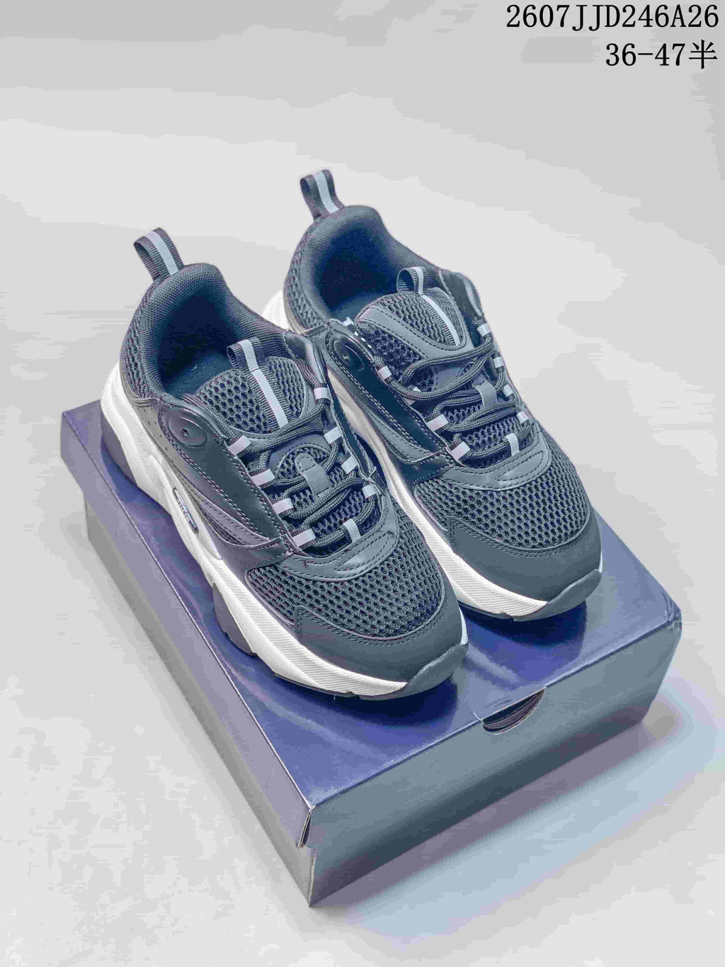 Pair of black and white Dior low-top sneakers displayed on a shoe box, showing the rounded toe, layered upper, and thick sole.