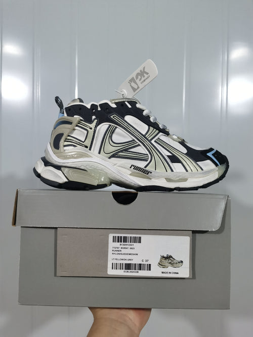 White and black 0623 Runner sneaker shown on its box, with cream and blue accents and a chunky outsole.