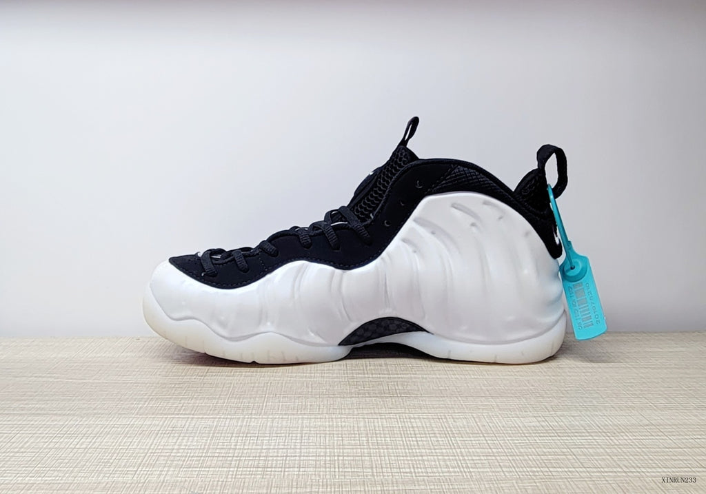 Side profile of a white Nike Air Foamposite One sneaker with black collar and turquoise tag