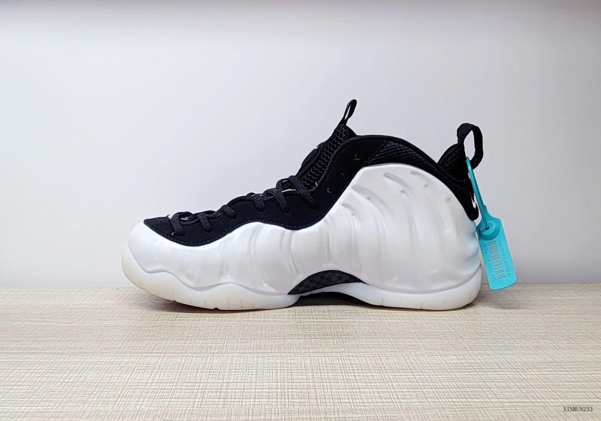 Side profile of a white Nike Air Foamposite One sneaker with black collar and turquoise tag