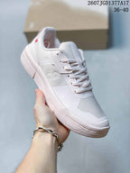 Angled side view of the white and pale pink sneaker showing the lace-up upper, textured side panel, padded collar, and layered outsole.