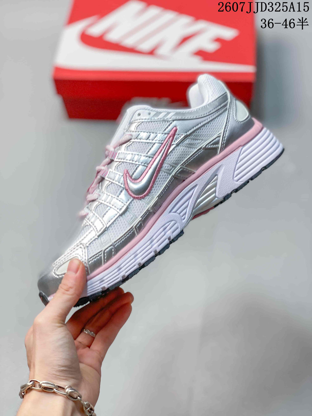 Side profile of the silver and pink sneaker showing layered panels, lace-up construction, Nike Swoosh branding, and a textured outsole.