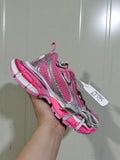 Close-up view of a pink and silver Nike sneaker with mesh panels, grey laces, and a segmented outsole.