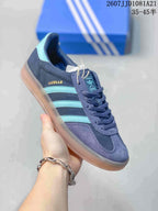 Angled side view highlighting the Gazelle lettering, turquoise stripes, navy upper, and gum-colored sole.