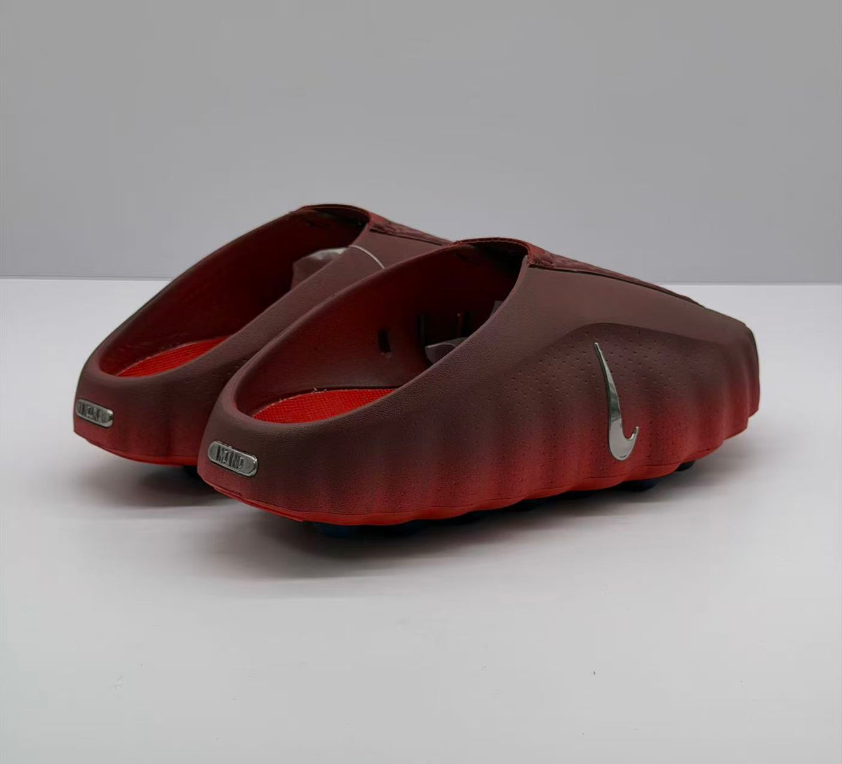 Rear three-quarter view showing the open heel design, side swoosh, and heel plaques.