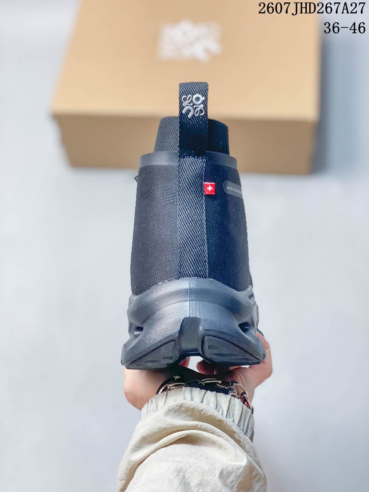 Rear view of a dark gray high-top sneaker showing the heel pull tab, ankle collar, small red side detail and sculpted outsole.