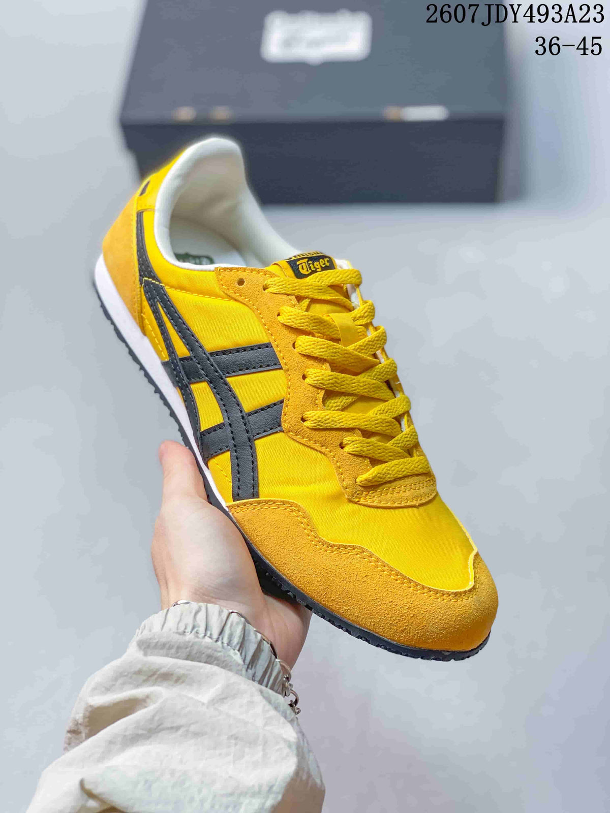 Angled side view of the yellow and black low-top sneaker with branded tongue and lace-up front.