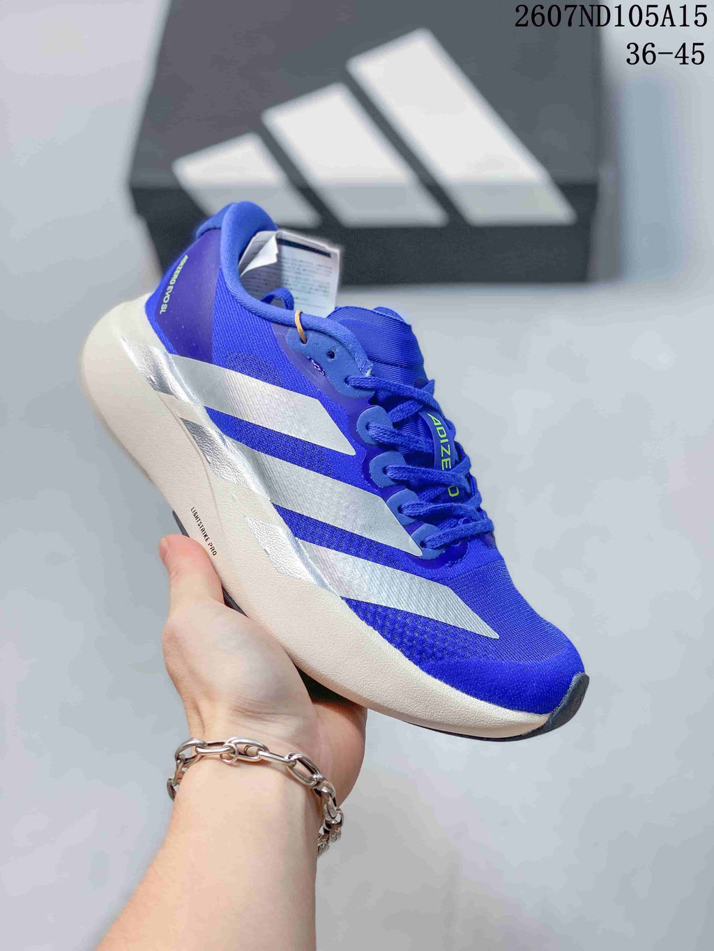 Side view of a blue and white Adidas Adizero sneaker showing the contrast stripes and low-profile sole.