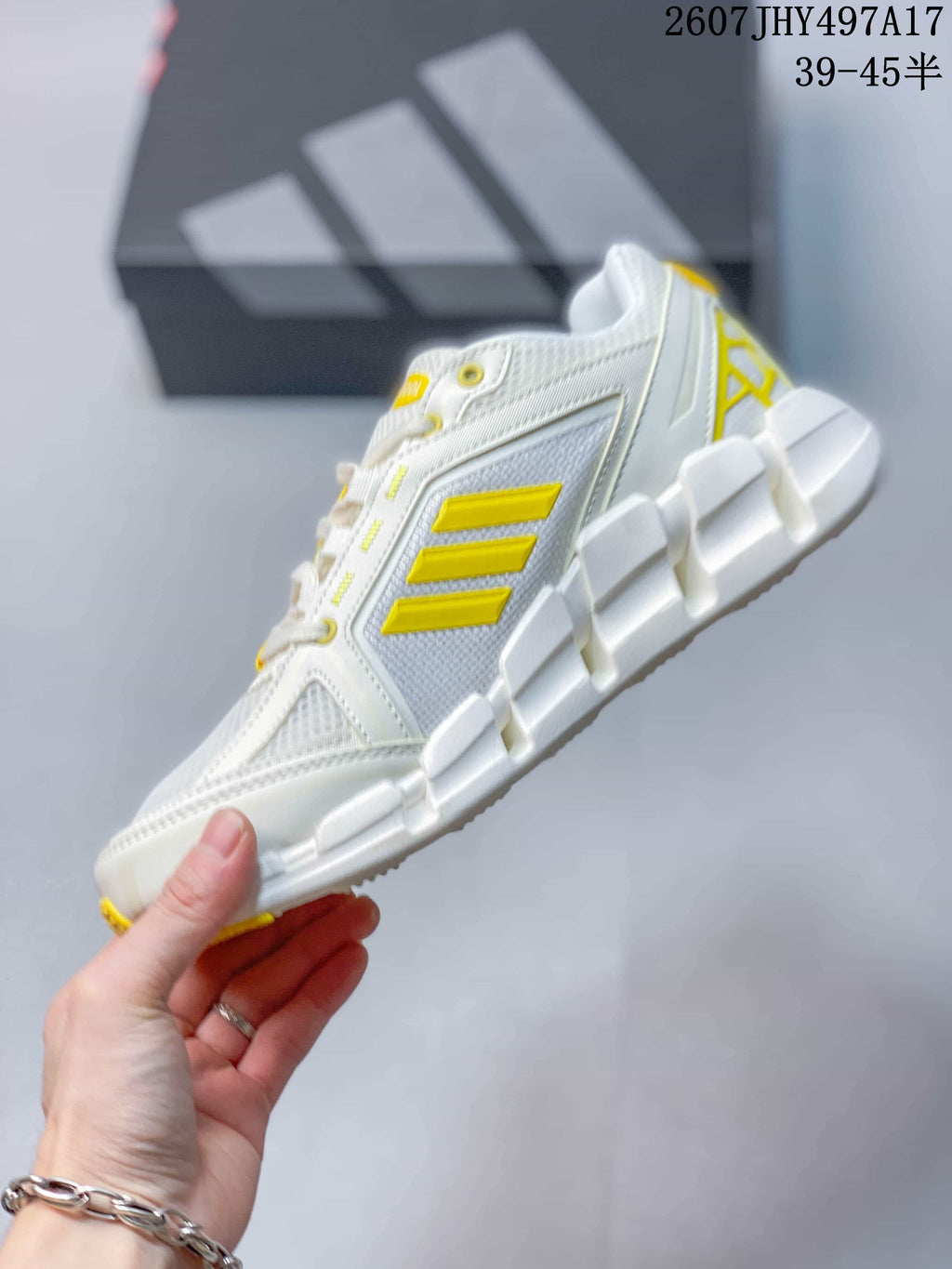 Side profile highlighting the mesh-style upper, yellow three-stripe detailing, TPU support elements, and segmented sole.