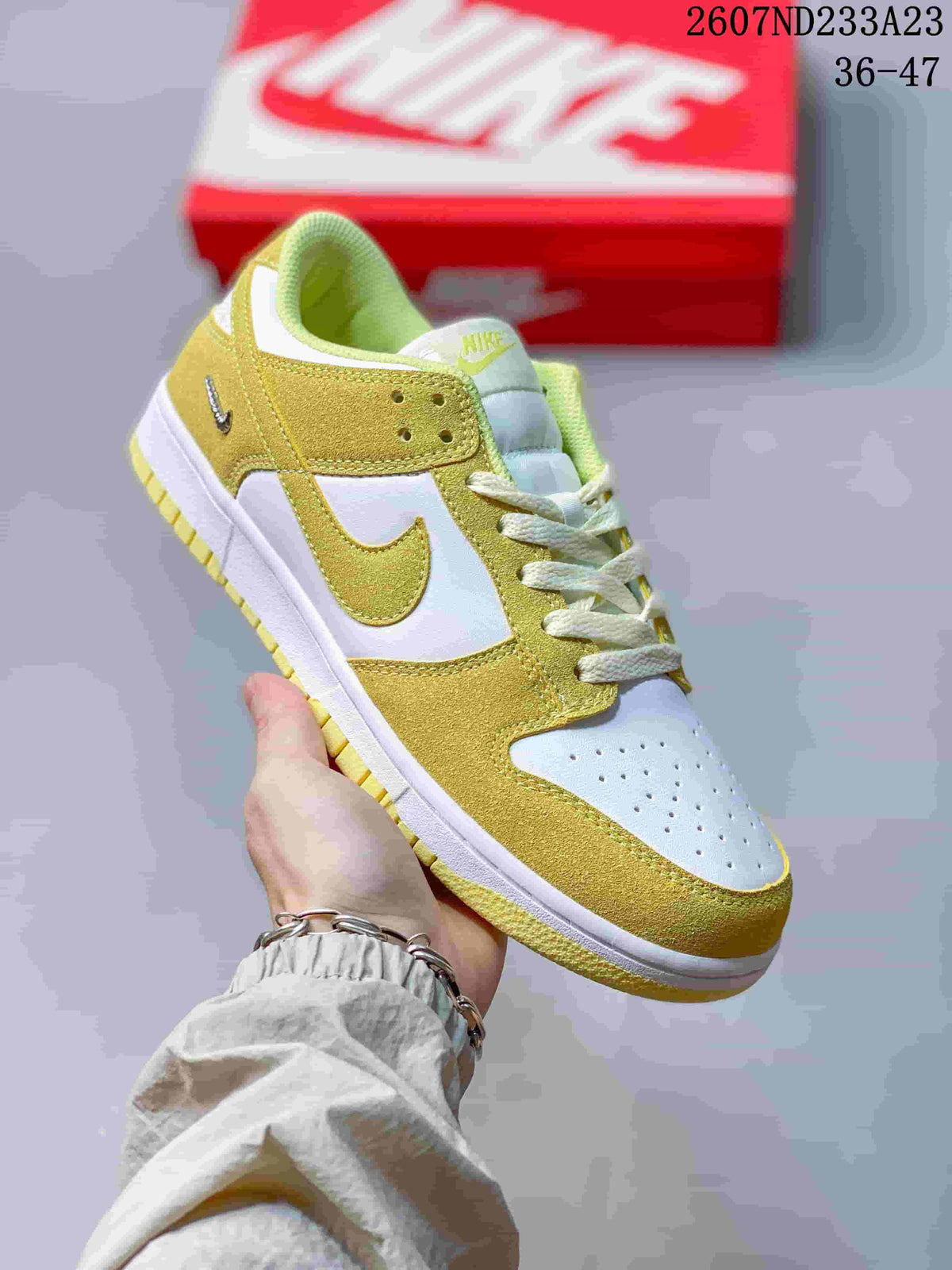 Close-up side view of a white and yellow-gold low-top sneaker showing the swoosh, laces, and perforated toe box.