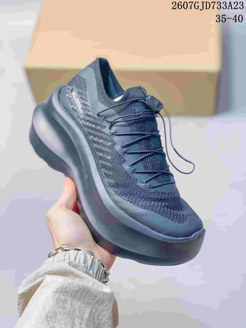 Angled side view of the black sneaker showing Salomon branding, textile-style panels, and thick dark sole.