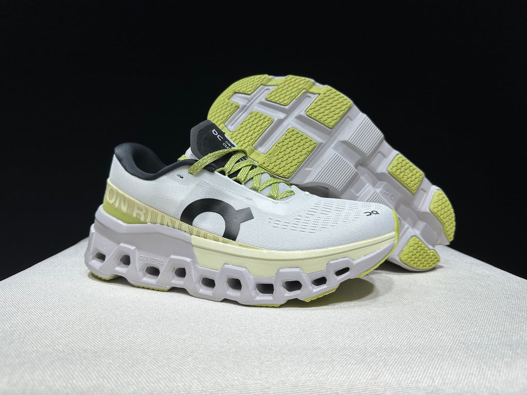 White and lime Cloudmonster 2 shoes, shown from the side with one shoe turned to display the sole.