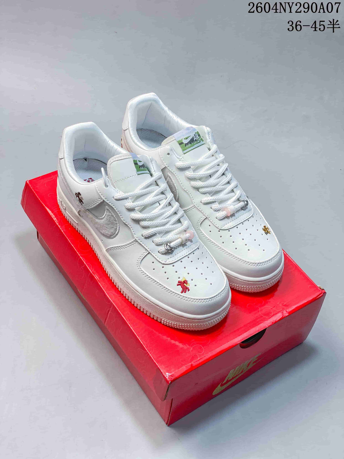 Pair of white low-top Nike Air Force 1 sneakers with embroidered horse-themed details, displayed on a red decorative shoe box.