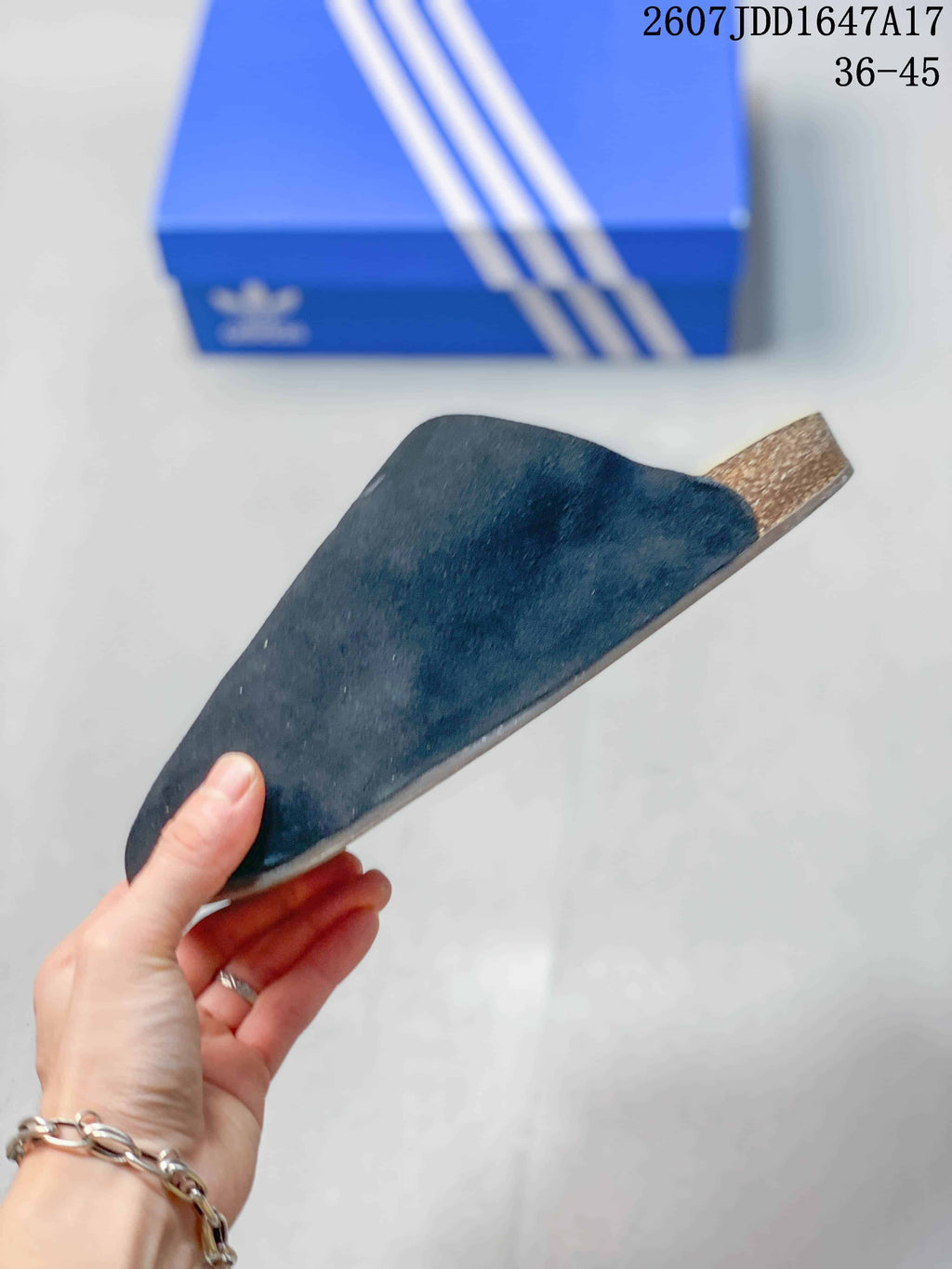 Side view of a black adidas slide showing the covered upper, flat sole profile, and brown-toned sidewall.