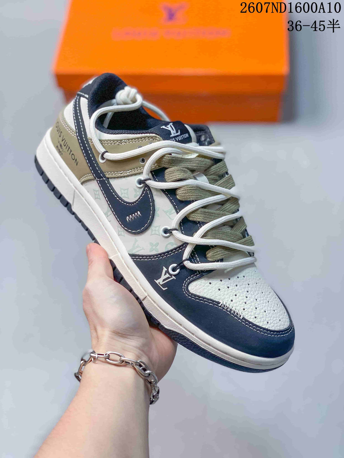 Three-quarter side view of the sneaker showing navy and cream overlays, olive panels, patterned side sections, and a dark rubber outsole.