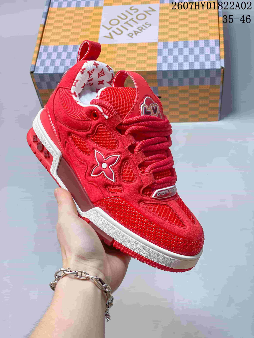 Close-up of a red Trainer-style sneaker showing layered panels, mesh sections, and side emblem.