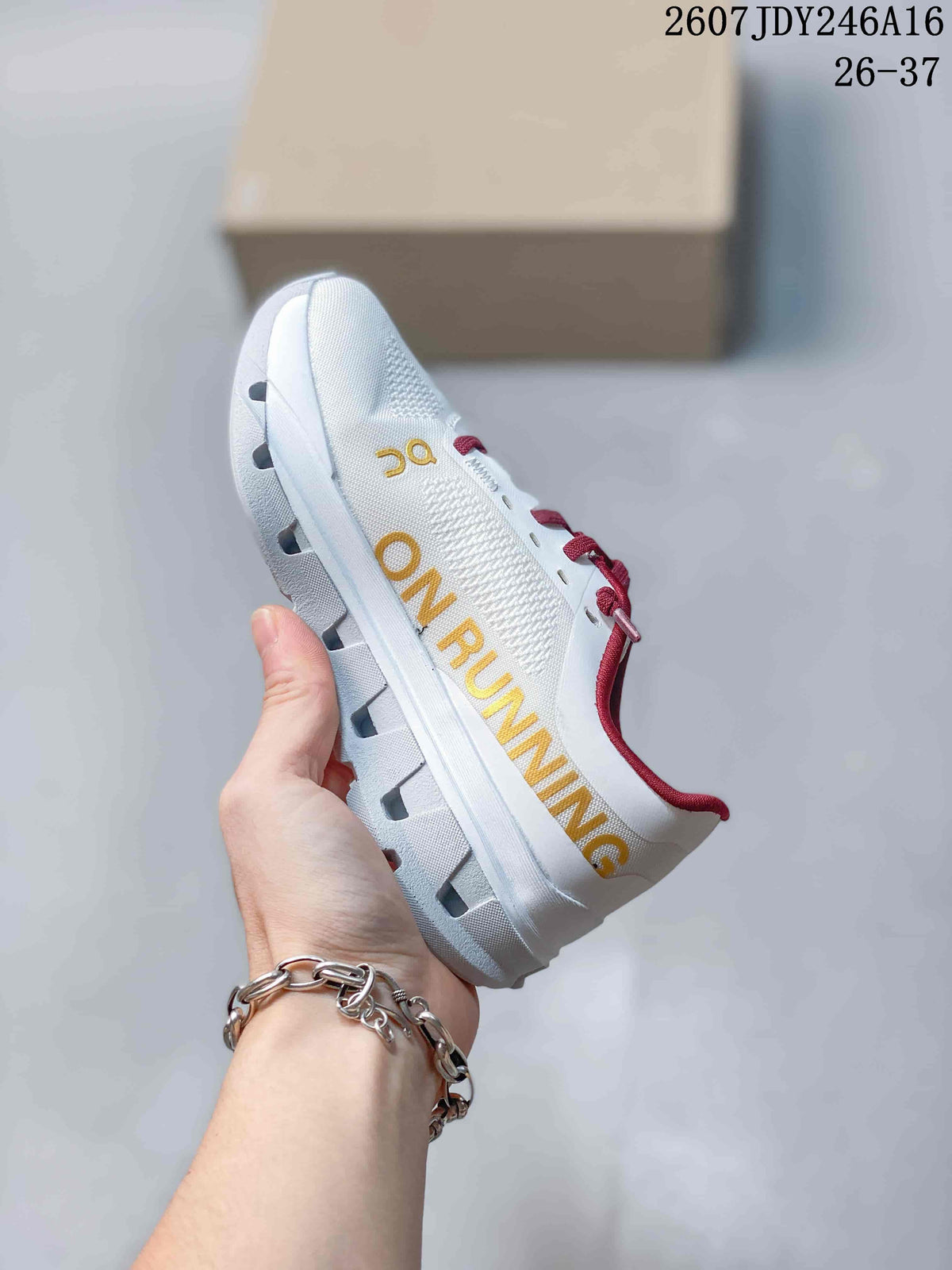 Side view of a white On running shoe with large yellow branding, burgundy laces, and a chunky segmented sole.