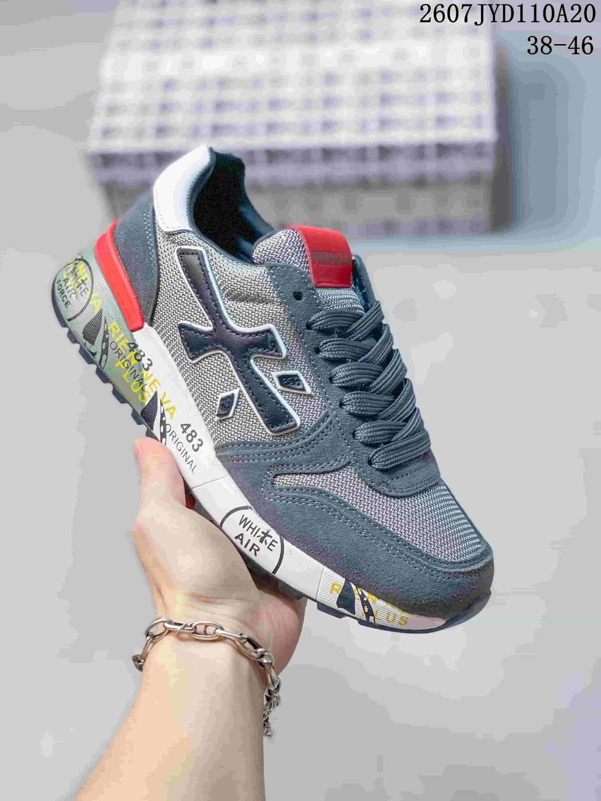Dark gray Premiata sneaker with a red tongue accent and contrasting side detail.