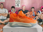 Side profile of an orange Nike basketball shoe with a patterned side panel and white midsole.