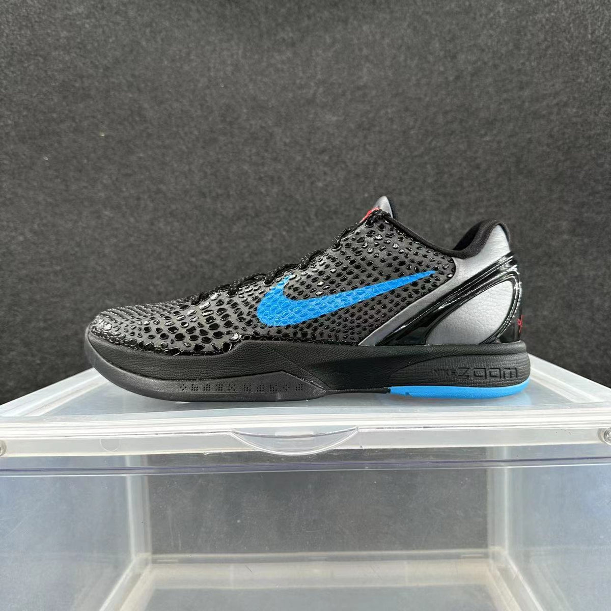 Side view of a black low-top Nike sneaker with a bright blue Swoosh and blue outsole accent.