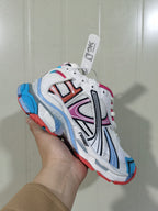 Angled close-up of the Runner sneaker showing the multicolor side overlays, white mesh construction and blue-and-red sole accents.