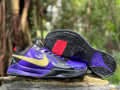 Nike Kobe 5 basketball shoes in purple, black and gold, shown from the side with the outsole visible.